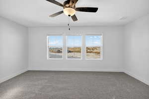 Spare room with dark colored carpet and a ceiling fan