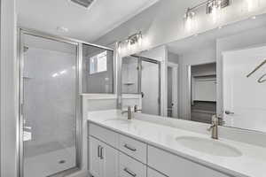 Full bath featuring double vanity and a shower stall