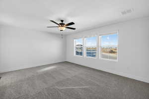 Empty room with dark colored carpet and ceiling fan