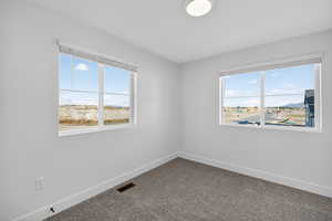 Spare room with dark carpet and plenty of natural light