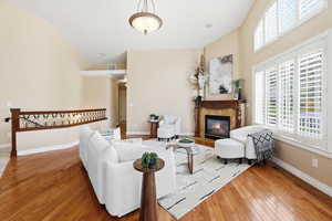 Family room featuring light wood-type flooring, a high end fireplace, and a high ceiling
