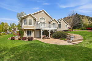 Back of property with a lawn, a patio, stucco siding, and a deck