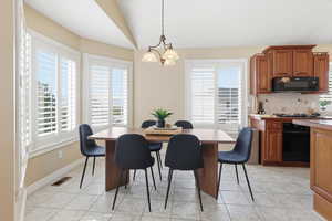 Dining space featuring light tile patterned floors, hanging lights, and lofted ceiling