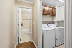 Laundry area with a textured ceiling, independent washer and dryer, light wood-style floors, and cabinet space