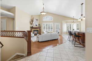 Living area with light tile patterned floors, a glass covered fireplace, and lofted ceiling
