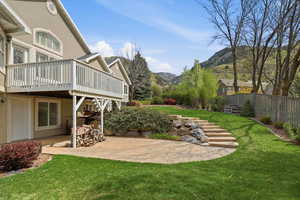 View of green lawn featuring a patio area, a deck with mountain view, and oil tank