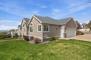 View of side of home featuring an attached garage, stucco siding, a lawn, concrete driveway, and a shingled roof