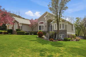 View of front of home featuring stone siding, stucco siding, and a front yard