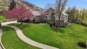 View of front of house featuring stone siding, a front yard, and stucco siding