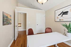 Home office with lofted ceiling and wood finished floors