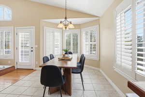 Dining room featuring light tile patterned floors, hanging lights, and lofted ceiling