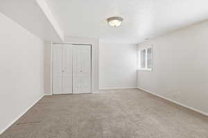 Unfurnished bedroom featuring a textured ceiling, carpet floors, and a closet