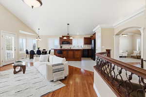 Family room with arched walkways, light wood finished floors, and vaulted ceiling