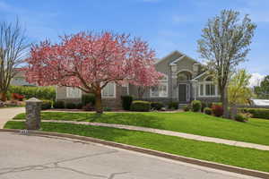 View of front of house with stone siding, a front lawn, and stucco siding