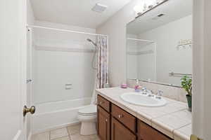 Full bathroom with vanity, a textured ceiling, shower / bath combo, and light tile patterned floors
