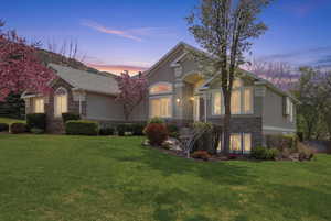 View of front of property featuring stone siding, stucco siding, and a lawn