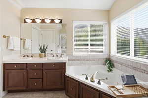 Bathroom featuring double vanity, a jetted tub, ensuite bathroom, and light tile patterned floors