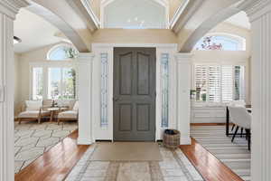 Entryway featuring inlaid floor details, arched walkways, vaulted ceiling, and light wood-type flooring