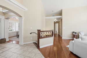 Corridor featuring light wood-style flooring, arched walkways, a high ceiling, and decorative columns