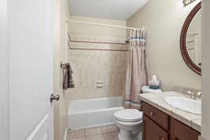 Bathroom featuring vanity, a textured ceiling, light tile patterned floors, and shower / tub combo
