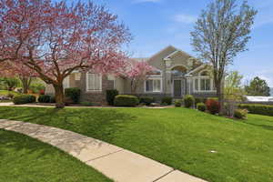 View of front of home with stone siding, a front yard, and stucco siding