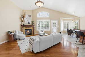 Family room area with light wood-style flooring, a fireplace, and lofted ceiling