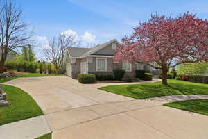 View of front facade with a front yard, stucco siding, driveway, stone siding, and an attached garage