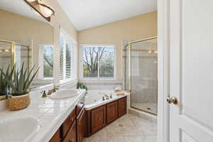 Bathroom with a stall shower, vaulted ceiling, a whirlpool tub, double vanity, and light tile patterned floors