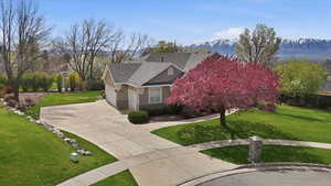 View of front of home featuring stone siding, a garage, roof with shingles, concrete driveway, and a mountain view