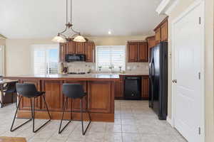 Kitchen featuring wood finish cabinetry, a kitchen bar, and black appliances