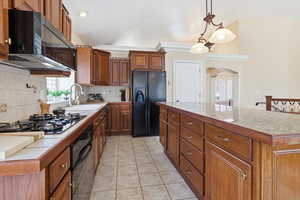 Kitchen with wood finish cabinetry, black appliances, lofted ceiling, tasteful backsplash, and decorative light fixtures