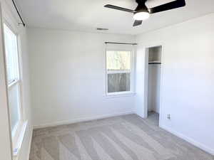 Unfurnished bedroom with light colored carpet, a closet, and a ceiling fan