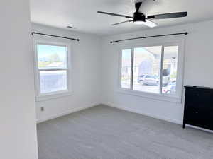 Empty room with light carpet, a ceiling fan, and healthy amount of natural light