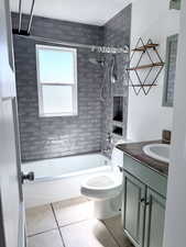 Bathroom with vanity, bathtub / shower combination, and light tile patterned floors