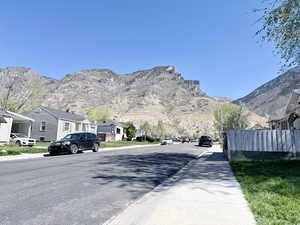 View of asphalt street with sidewalks, a mountain view, a residential view, and curbs