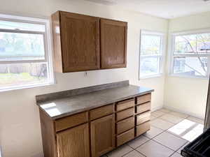 Kitchen with light tile patterned floors, wood finish cabinets, and dark countertops