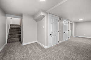 Finished basement featuring stairs and carpet