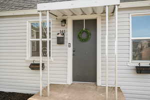 Doorway to property featuring roof with shingles