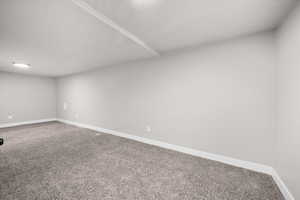 Carpeted spare room featuring baseboards