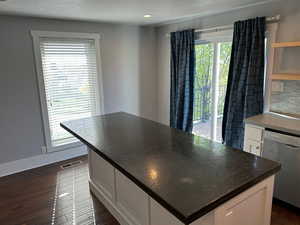 Kitchen with a center island, white cabinetry, dark wood-type flooring, dishwasher, and open shelves