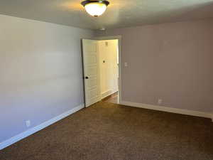 Spare room with dark colored carpet and a textured ceiling