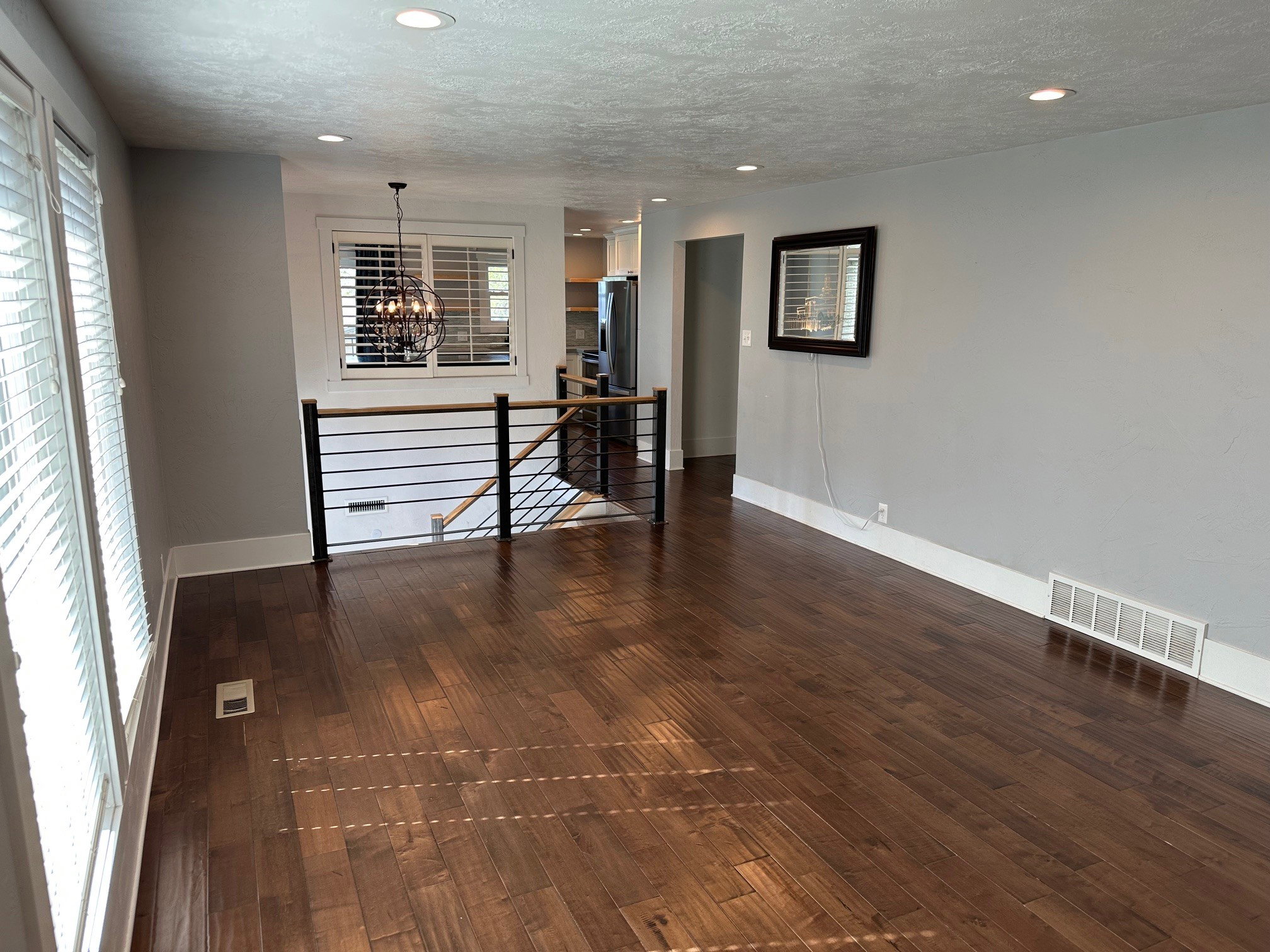 Empty room with dark wood finished floors, hanging lights, and a textured ceiling