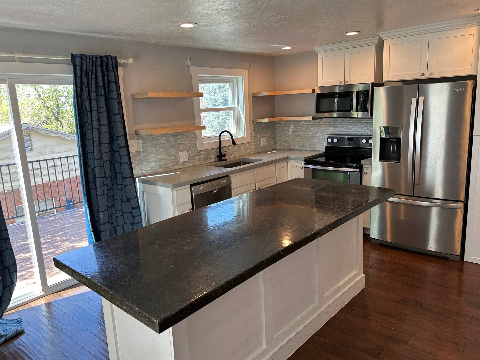 Kitchen with white cabinets, stainless steel appliances, dark wood finished floors, a center island, and recessed lighting