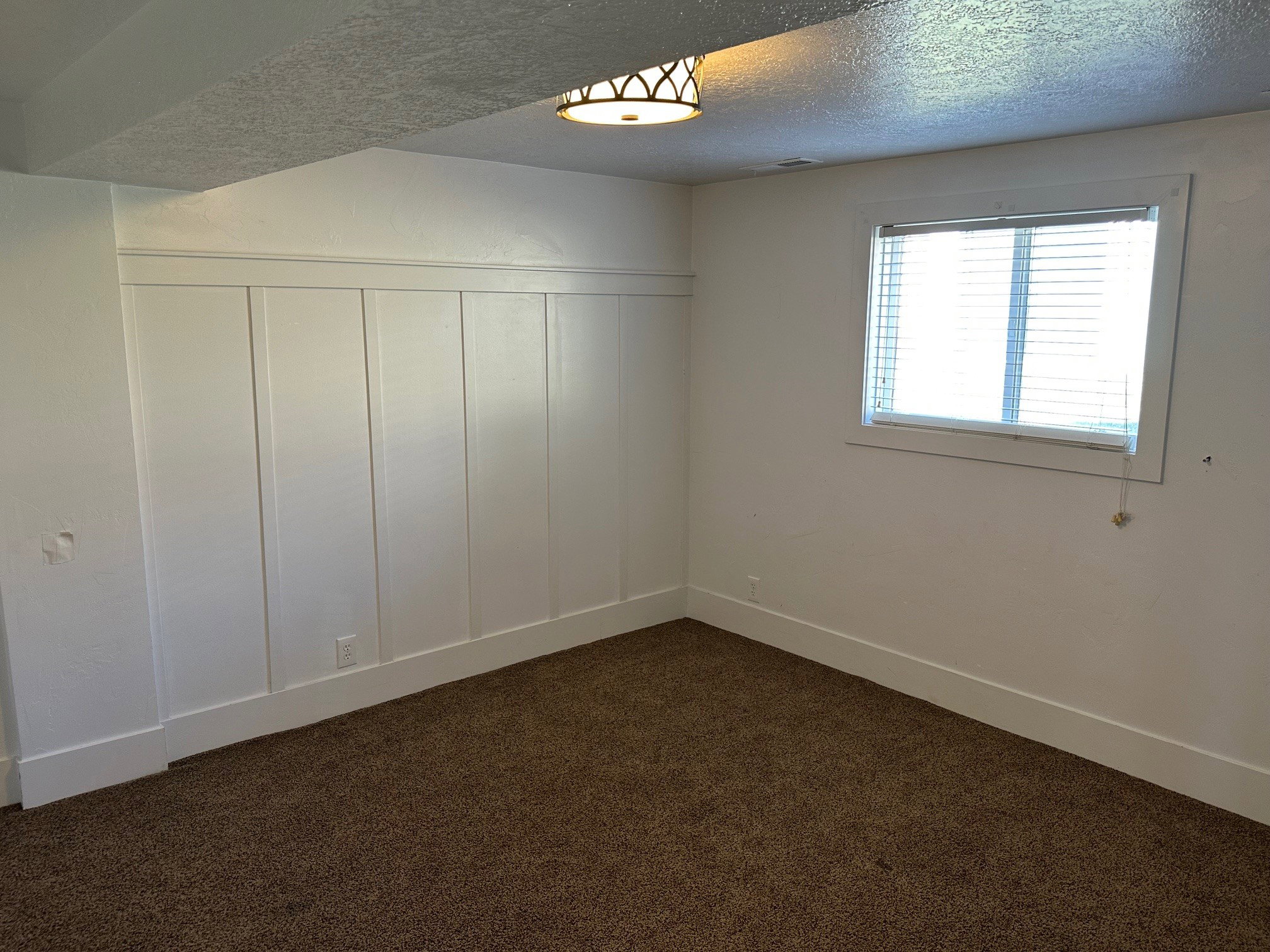 Spare room with dark carpet, a textured ceiling, a decorative wall, and wainscoting