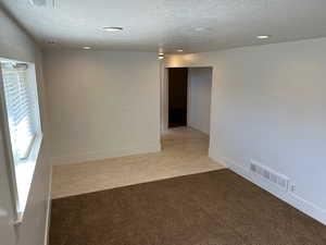 Empty room with light carpet, a textured ceiling, recessed lighting, and light wood finished floors