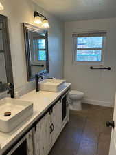 Bathroom with double vanity and dark tile patterned flooring