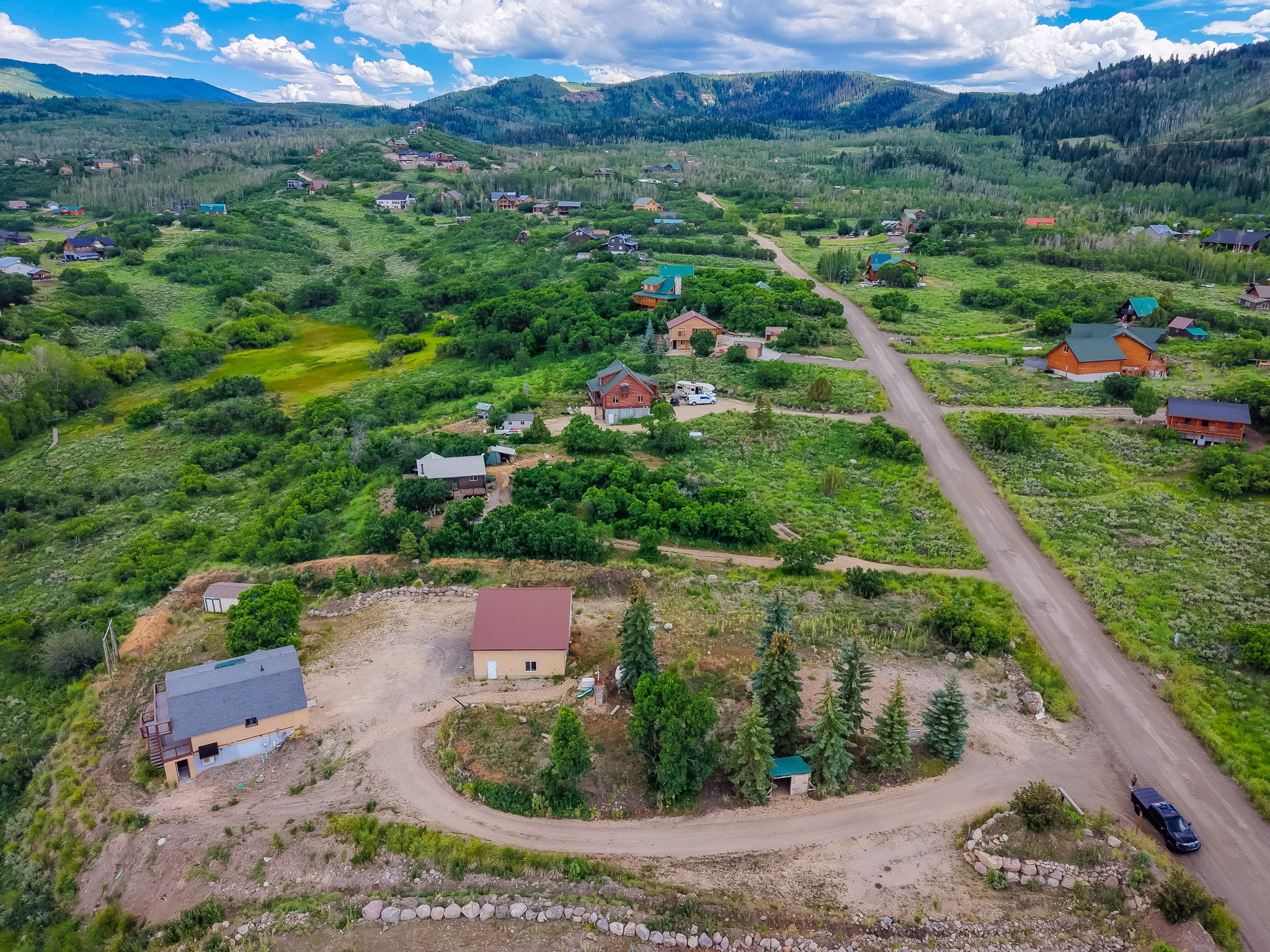 Expansive mountain terrain featuring multiple residences and a winding unpaved road