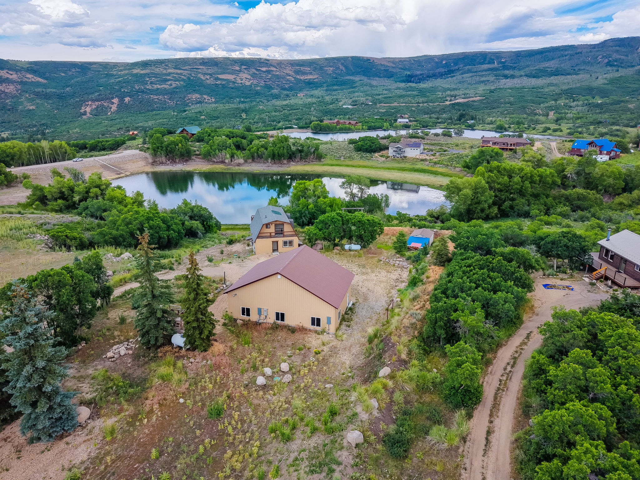 Aerial perspective revealing a property situated on a sloped landscape with a brown-roofed structure