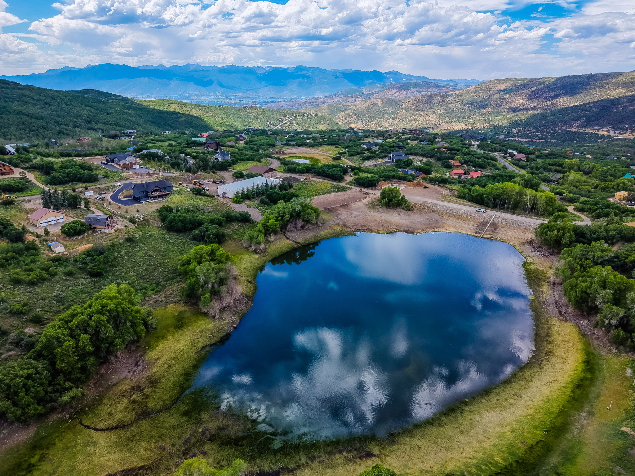 Expansive lake featuring a natural shoreline, surrounded by green vegetation and distant mountains