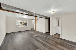 Basement with a paneled ceiling and dark wood-type flooring